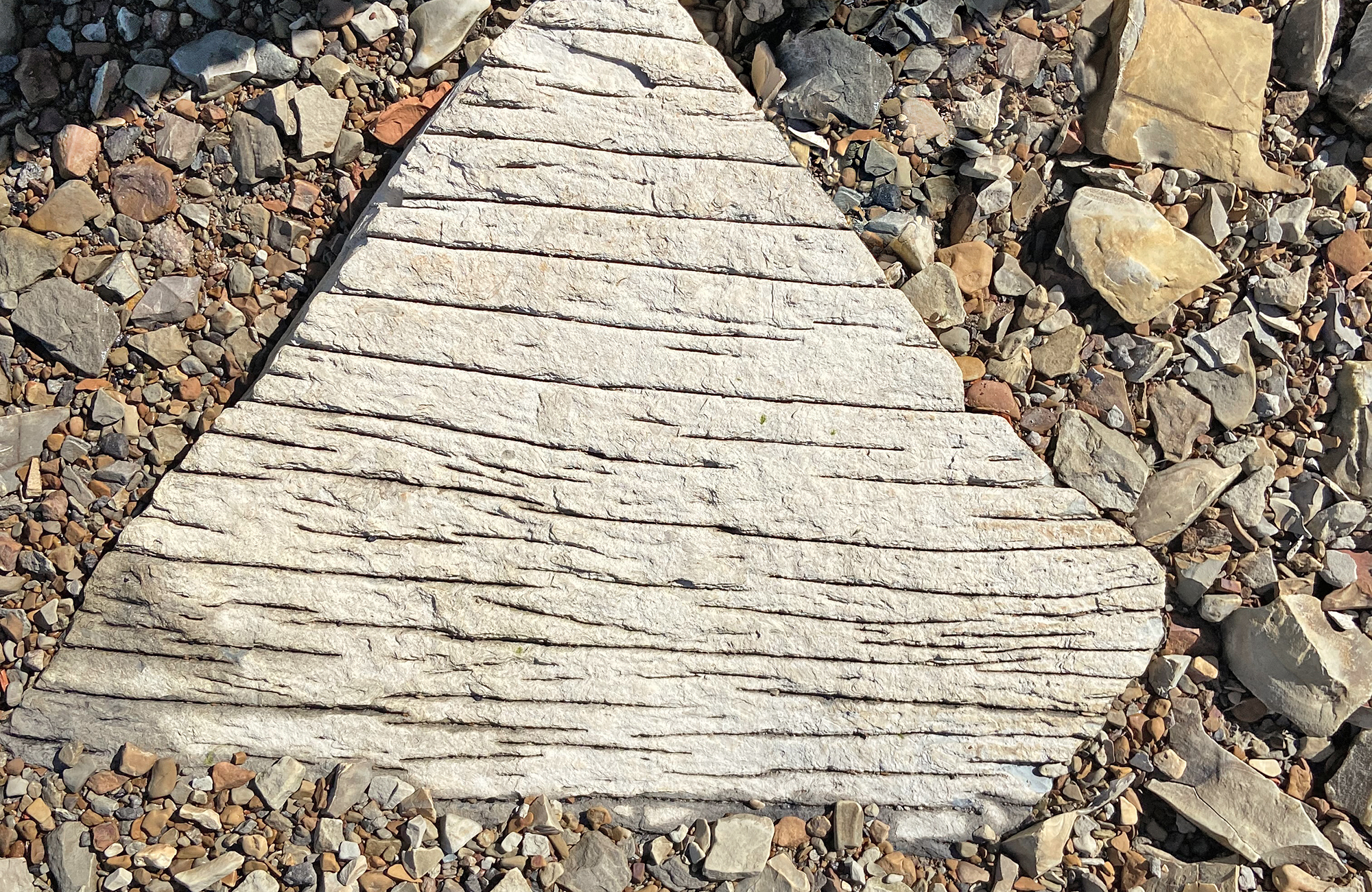 Rock in the shape of a triangle with many grooves cut into it.