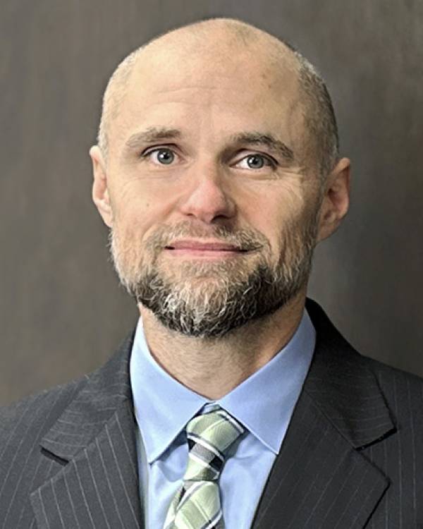 Headshot of Jonathan Labonte wearing a striped, gray suit jacket, a blue shirt and a light green tie.