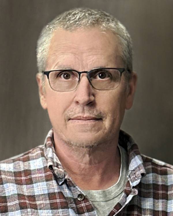 Headshot of Steve Chittick wearing a maroon and gray plaid shirt.
