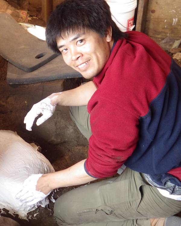 Photo of a man applying plaster around a fossil.