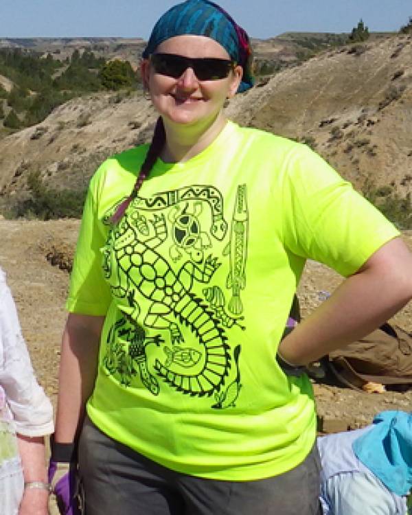 Becky Barnes wearing a bright yellow shirt and sunglasses standing outside.
