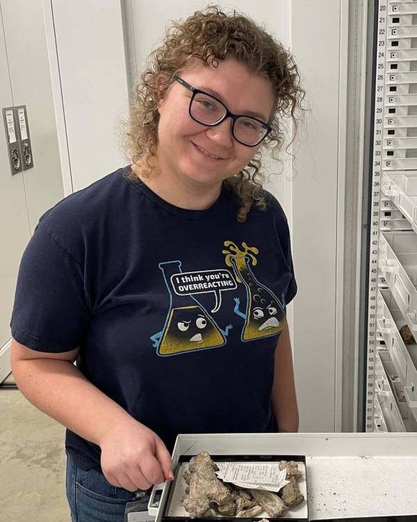 Photo of a woman next to shelves and fossils.