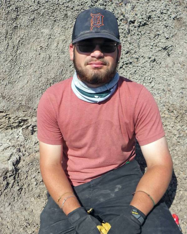 Photo of a man sitting in the dirt.
