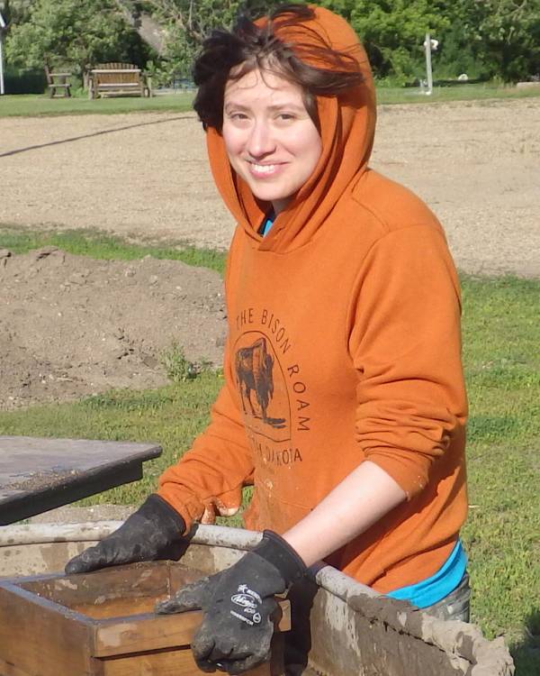 Photo of a person wearing an orange hooded sweatshirt washing fossils.