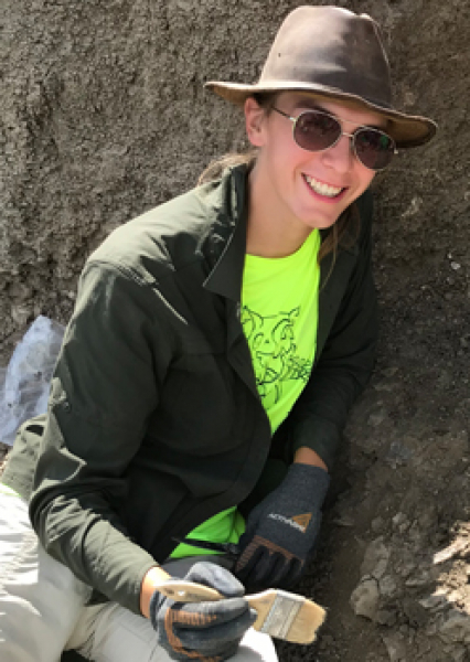 Intern Hayley Orlowski holds a brush in hand at the Bismarck dinosaur site