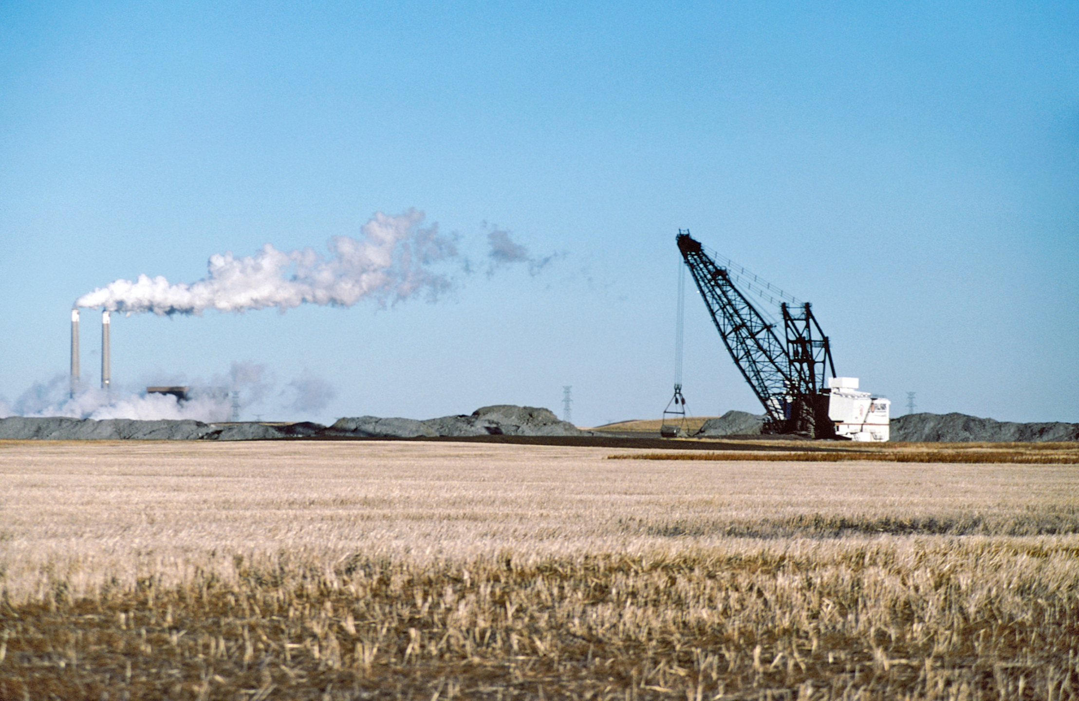 Photo of a power plant and a coal dragline next to a field.