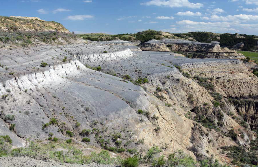 A white layer running through a blueish gray section of a rock formation.