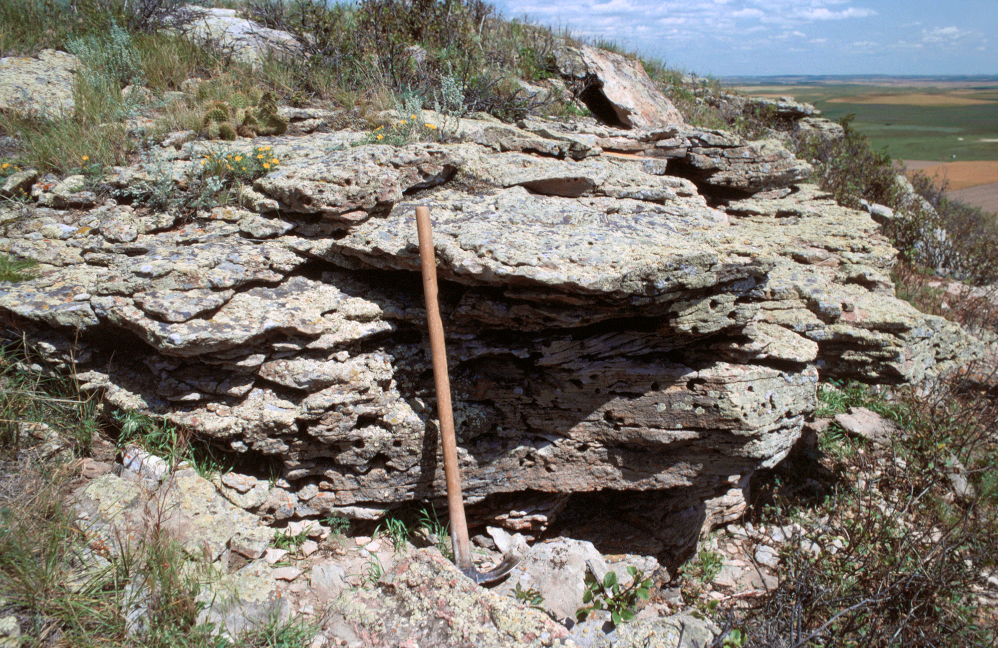 A photo of a pick axe leaning against a rock formation.