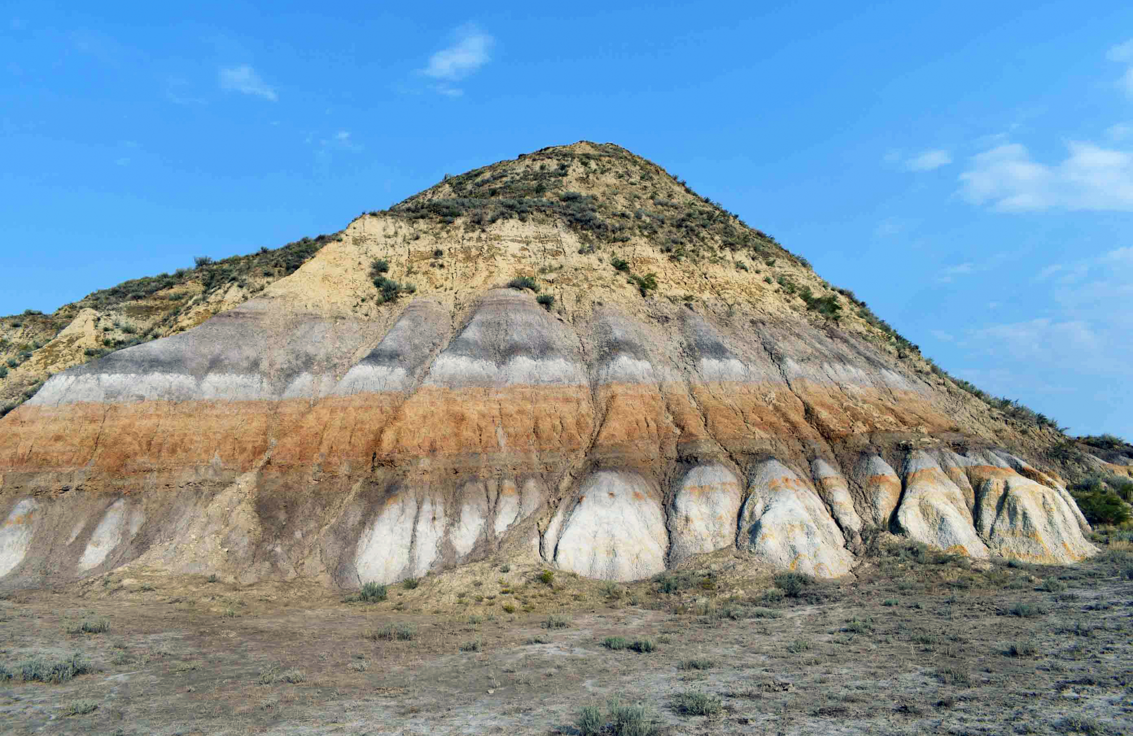 A photo of a colorful rock formation and bright blue sky.