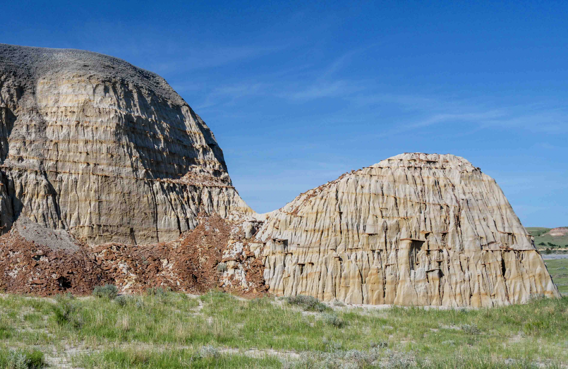 Photo of a unique formation, green grass and blue sky.