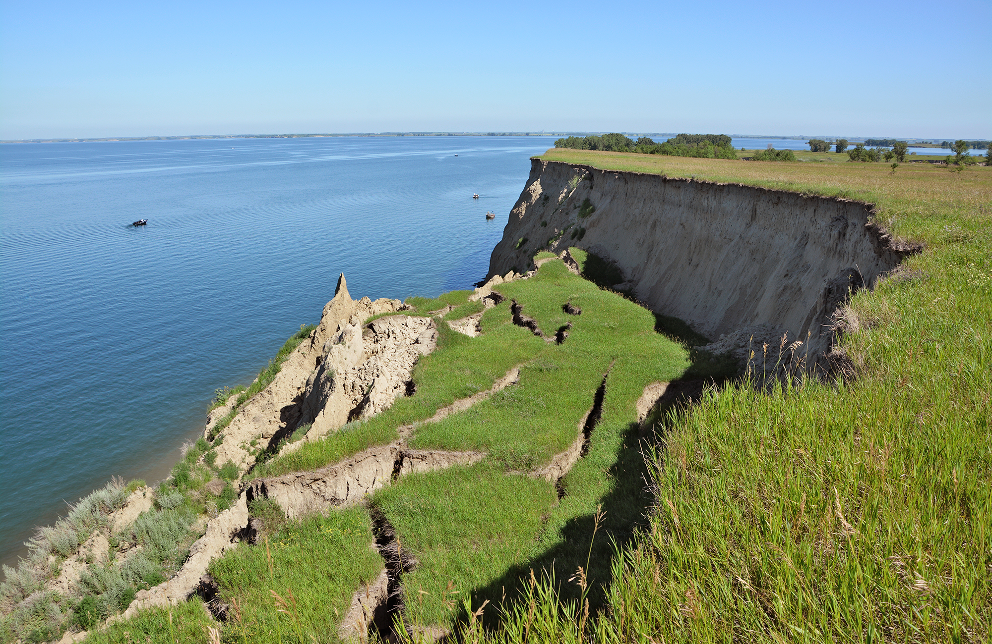 A photo of a lake with a bank that has slid down.