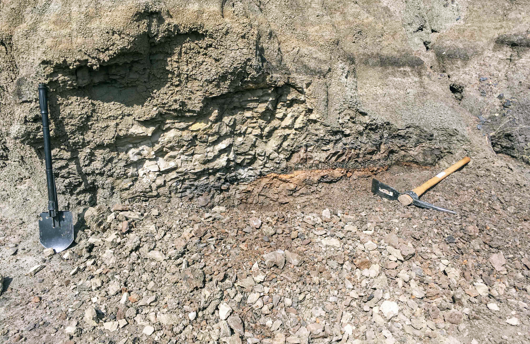 A pick axe and shovel in the dirt.