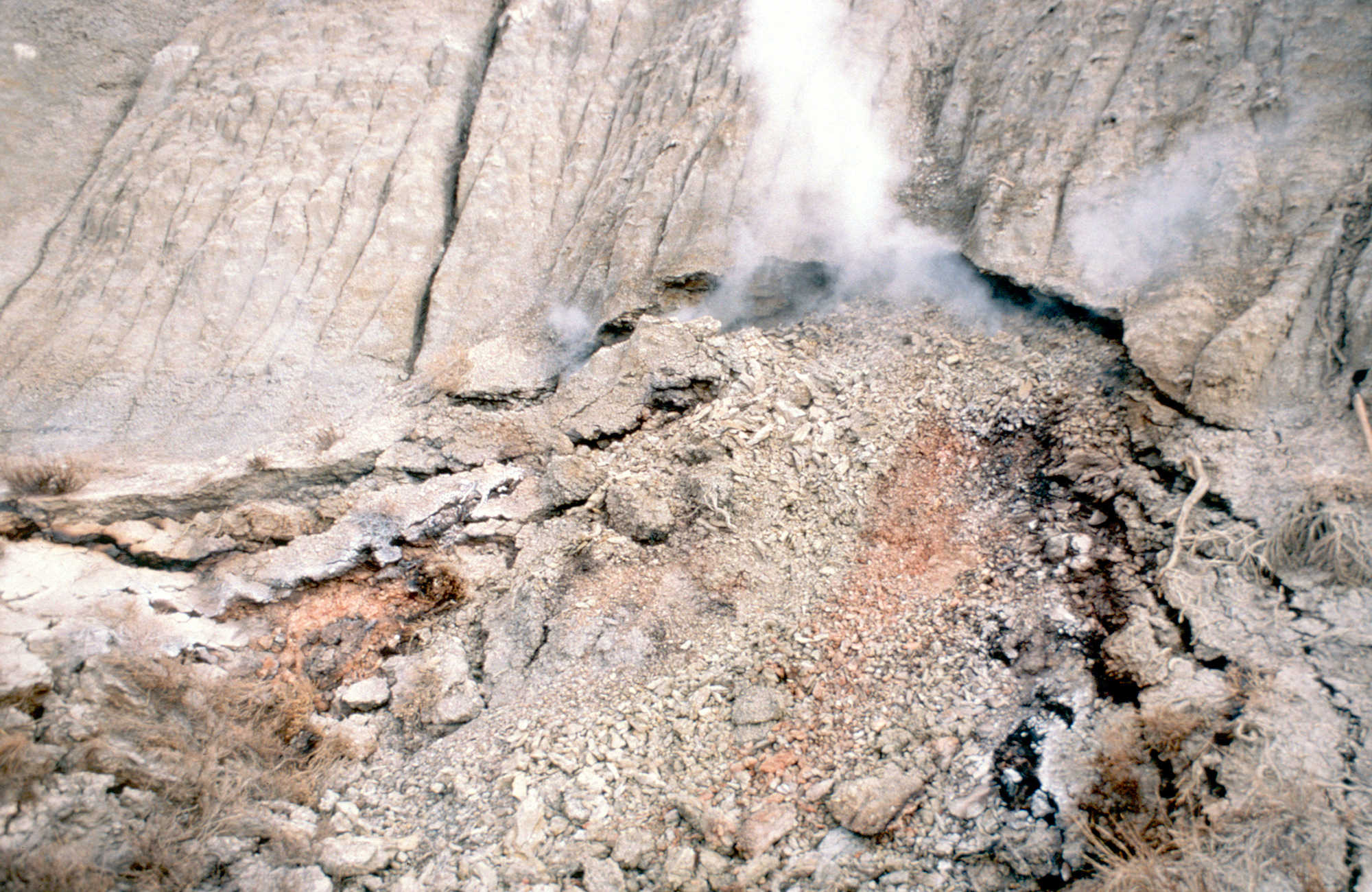 Photo of white smoke coming up from a coal seam in the ground.