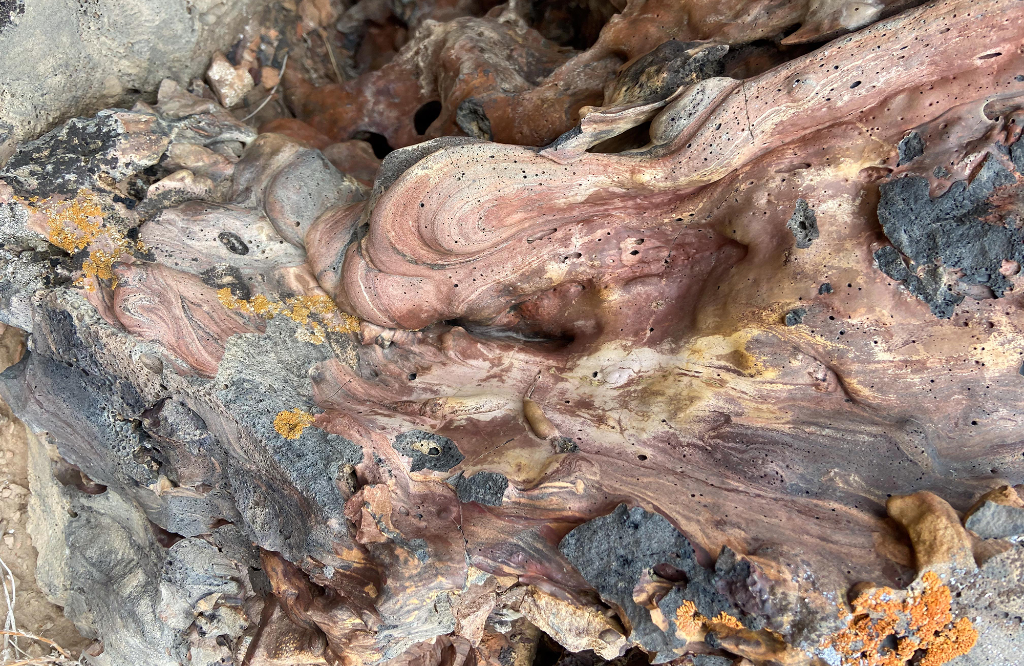A reddish irregular rock that is swirled with different colors.