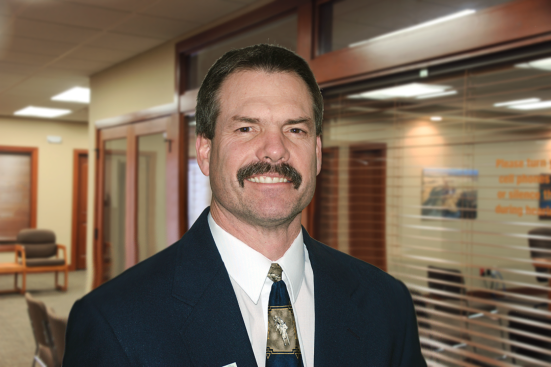 Mark Bohrer in suit and tie standing in office.