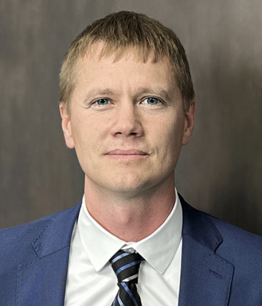 A headshot of a man, Tim Nesheim, in a suit and tie.