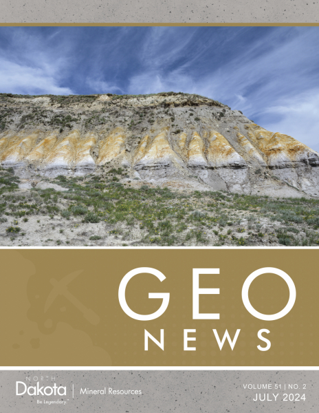 A photo of orange-stained white rock and gray zones of a formation on the slope of a butte.