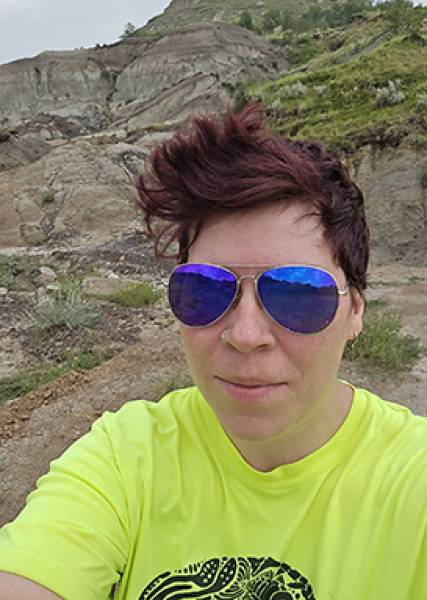 Selfie of Alex in front of dirt and grass