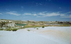 A portion of the old Fritz uraniferous mine located southwest of Belfield in Slope County. The photograph was taken in 1991, 
								shortly before the mine site was reclaimed by the North Dakota Public Service Commission. Water with a low pH and high uranium content has ponded at the base of one of the mine 
								pits. (Photo by E. Murphy, NDGS). 