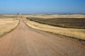 A clinker-covered road leading east to Lone Butte in McKenzie County. 
								The Killdeer Mountains are visible on the horizon. Photo by E. Murphy, NDGS). 